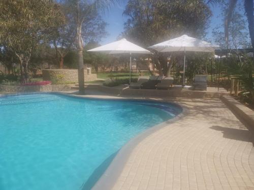 a large swimming pool with two umbrellas at La Fiato Luxury Lodge in Dalmada AH