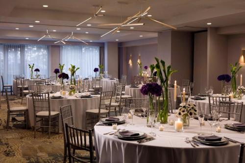 ワシントンにあるGlover Park Hotel Georgetownのテーブルと椅子(白いリネン付)が備わる宴会場