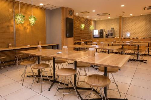 a restaurant with wooden tables and stools at Super Hotel Miyazaki Natural Hot Springs in Miyazaki