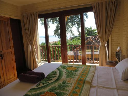 a bedroom with a bed and a large window at Jukung Dive Resort Bali AMED in Amed