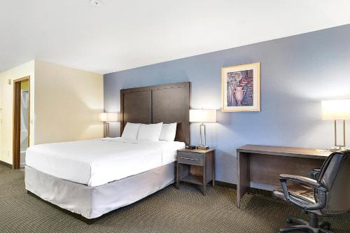 a hotel room with a large bed and a desk at Days Inn by Wyndham Ellensburg in Ellensburg