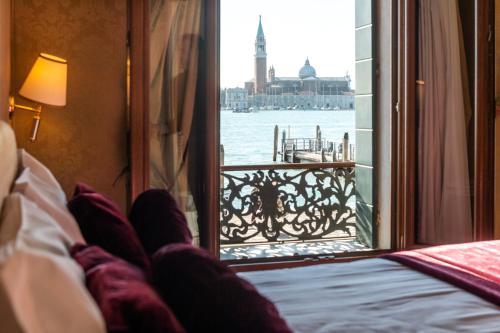 a person laying in bed looking out a window at the water at A Tribute To Music Residenza in Venice