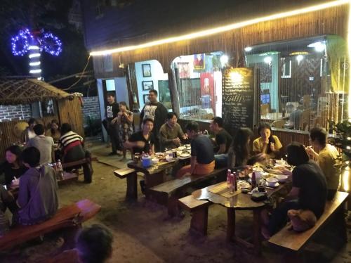 a group of people sitting at tables in a restaurant at night at Soe Ko Ko Beach House & Restaurant in Ngwesaung