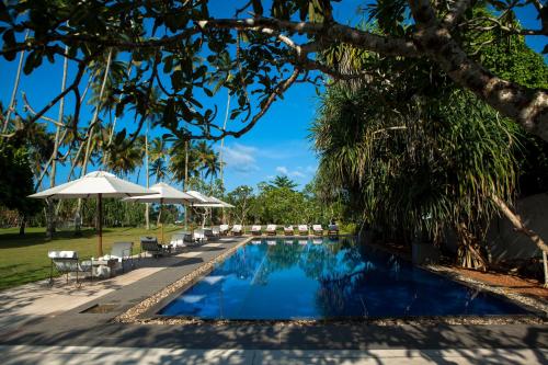 a swimming pool with chairs and umbrellas at Club Villa in Bentota