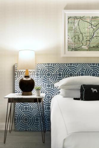 a bedroom with a bed and a table with a lamp at Kimpton Rowan Palm Springs Hotel by IHG in Palm Springs