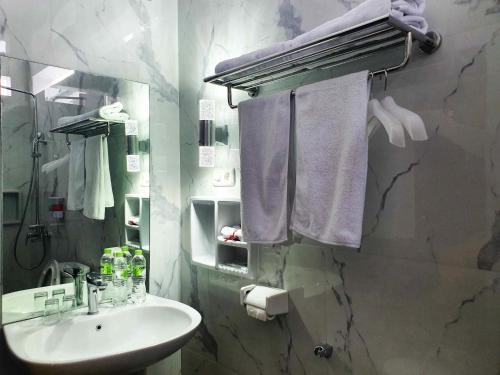 een badkamer met een wastafel en een douche met handdoeken bij Tiongkok Kecil Heritage Lasem in Lasem