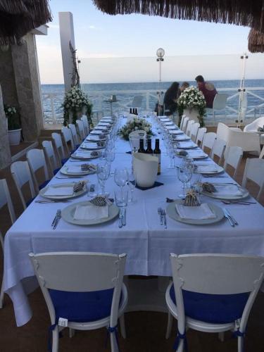a long table with white chairs and plates and wine glasses at B&B Villa S.Anna in Bari
