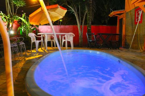 a swimming pool with an umbrella and a table and chairs at Pousada Recanto Domus in Ubatuba