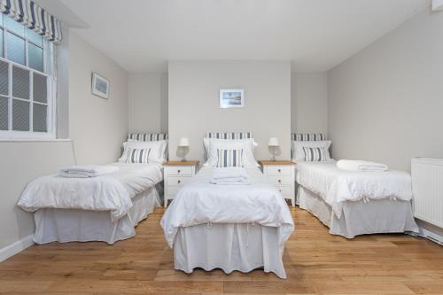 drie bedden in een kamer met witte muren en houten vloeren bij Central Brighton Town House in Brighton & Hove