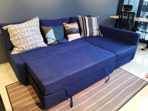 a blue couch with pillows on it in a living room at EkoCheras Balcony City View King Bed Rooftop Pool High Speed Fibre Internet MRT Connection in Kuala Lumpur