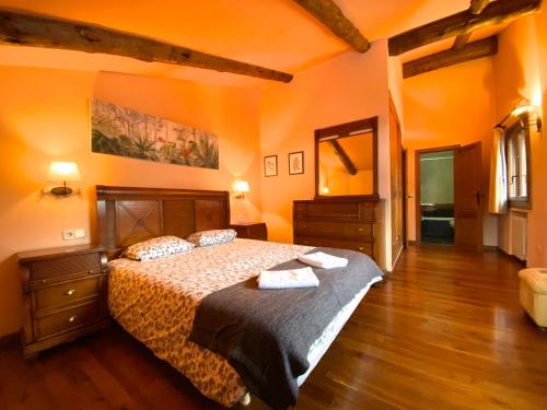 a bedroom with a large bed with orange walls and wooden floors at Isards, Atico rustico con chimenea en el tarter, zona Grandvalira in El Tarter