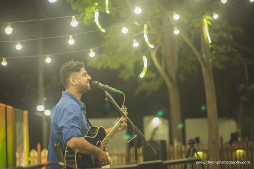 a man singing into a microphone while holding a guitar at Tuk Tuk Hostel Negombo in Negombo