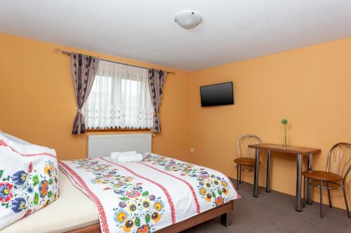 a bedroom with a bed and a window and a table at Penzión Goraľka in Ždiar