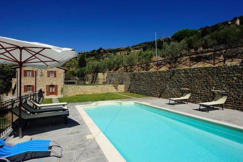 a swimming pool with two chairs and an umbrella at Agriturismo Il Torrino in Cortona