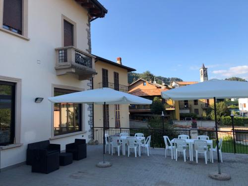a patio with white tables and chairs and umbrellas at Albergo Sala in Valbrona