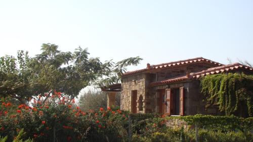 an old stone house with a garden and flowers at Caviro on the Beach in Moudhros