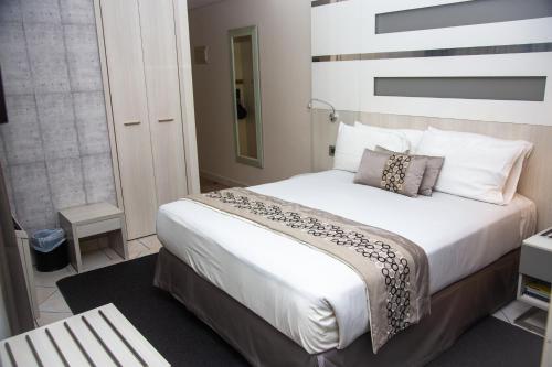 
a bed room with a white bedspread and pillows at Hotel 2001 in Maputo
