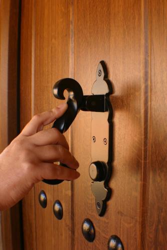 a person unlocking a wooden door with their hand at Apartamentos Rurales La Vega del Jerte in Jerte