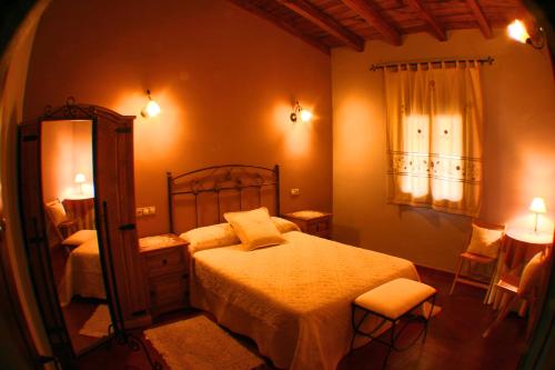 a bedroom with a bed and a mirror at Apartamentos Rurales La Vega del Jerte in Jerte