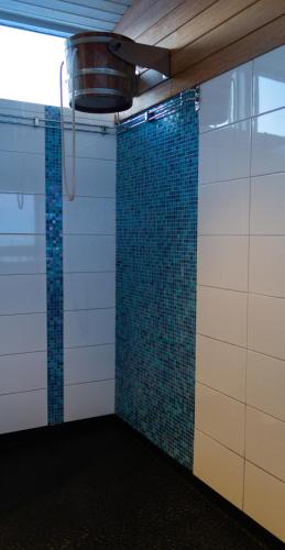 a room with a shower with blue tiles on the wall at Hotell Toppen in Storuman