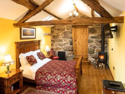a bedroom with a bed and a stone wall at The Wayside and Whisky Barn in Whitbeck