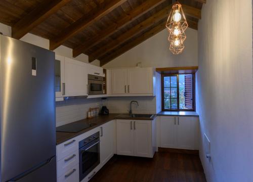 una cucina con armadi bianchi e lampadario pendente di Casa Rural Los Frailes a Los Llanillos