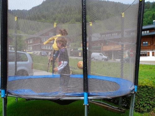 two children are playing on a trampoline at Ferienbauernhof Moosbrugger in Schoppernau
