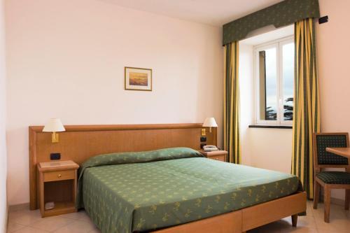 a bedroom with a green bed and a window at Hotel Riviera in Arenzano