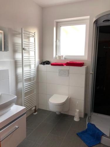 a white bathroom with a toilet and a window at Beatles in Clausen