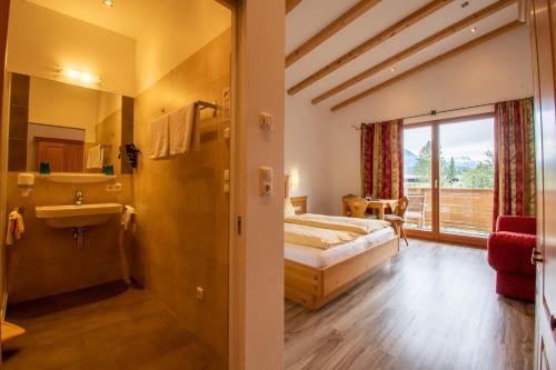 a bedroom with a bed and a bathroom with a sink at Pension Noella in Sankt Johann in Tirol