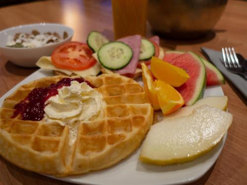 a plate of waffles and fruits and vegetables on a table at Hotell Toppen in Storuman