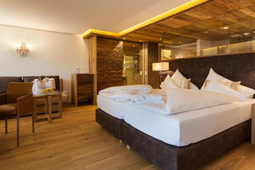 a bedroom with two beds and a table and a chair at Hotel Neuhaus in Saalbach-Hinterglemm