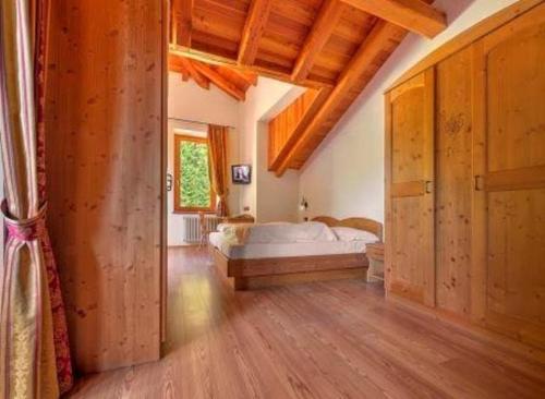 a bedroom with a bed in a room with wooden floors at Hotel Dal Bracconiere in Folgarida