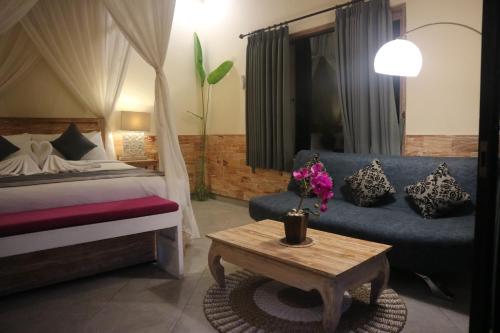 a bedroom with a bed and a couch and a table at Villa D'Uma in Ubud
