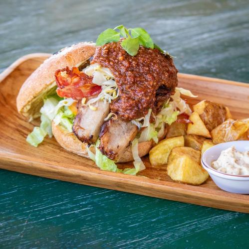 a sandwich on a wooden tray with chips and dip at PinkCoco Gili Trawangan - Constant Surprises - for Cool Adults Only in Gili Trawangan