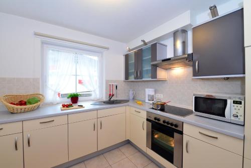 a kitchen with white cabinets and a microwave at Landhaus Thaler in Mittelberg