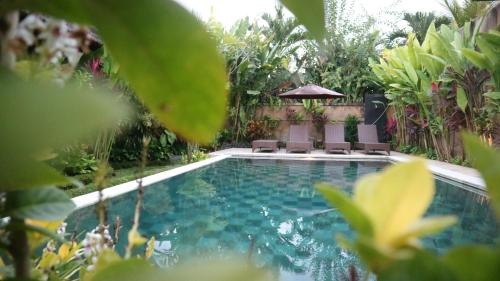 a swimming pool with two chairs and a gazebo at Villa D'Uma in Ubud