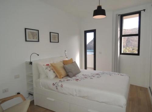 a white bedroom with a white bed with pillows at Hauzify I Apartamento Ruiz de Padron in San Sebastián de la Gomera