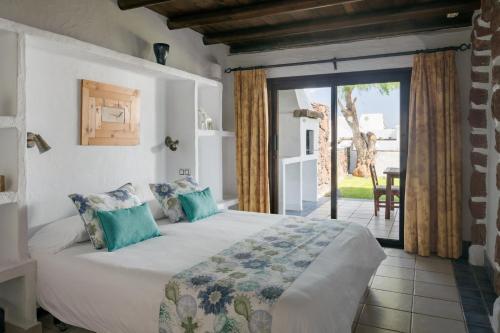 1 dormitorio con 1 cama y puerta corredera de cristal en Kamezí Boutique Hotel Villas, en Playa Blanca