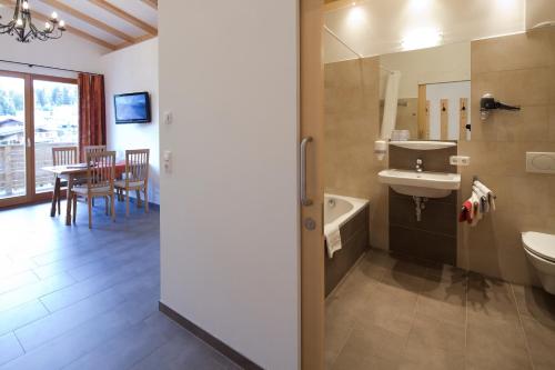 a bathroom with a sink and a toilet and a table at Pension Noella in Sankt Johann in Tirol