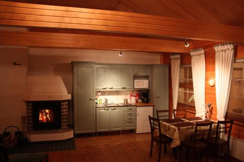 eine Küche mit einem Tisch und eine Küche mit einem Kamin in der Unterkunft Cottage Baydar in Jyräänkoski