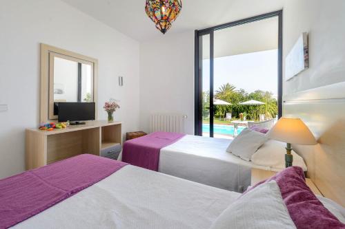 um quarto com 2 camas, uma televisão e uma janela em Villa Anur em San Jose de sa Talaia