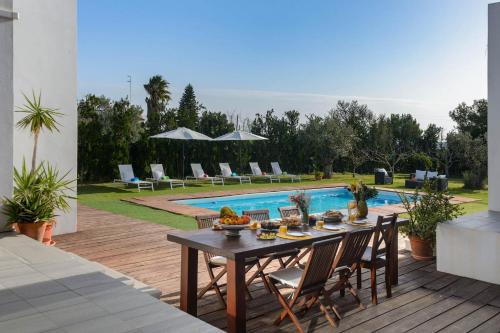 a wooden deck with a table and chairs next to a pool at Villa Anur in Sant Josep de Sa Talaia