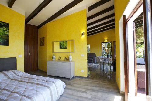 a bedroom with yellow walls and a bed and a dining room at Villetta Simonetta in Maccagno Superiore