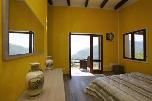 a yellow room with a bed and two vases on a table at Villetta Simonetta in Maccagno con Pino e Veddasca
