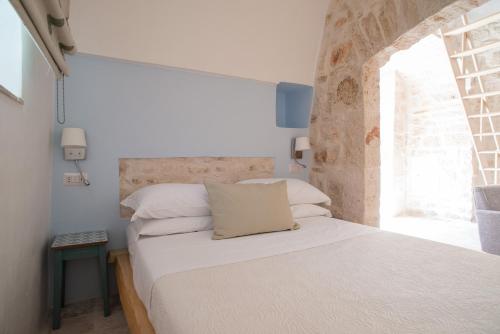 a bedroom with a white bed with a window at Trullidea in Alberobello
