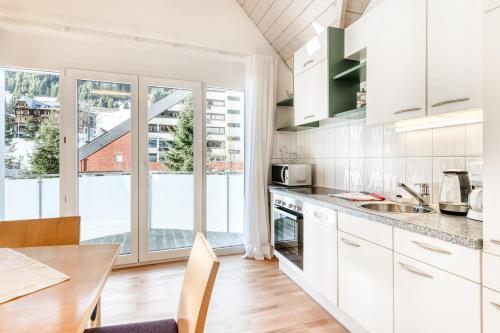 a kitchen with white cabinets and a table and a large window at Haus Capricorn - Appartement Mountain View in Gargellen