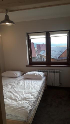 a bed in a room with two windows at Pokoje u Katarzyny in Rzepiska