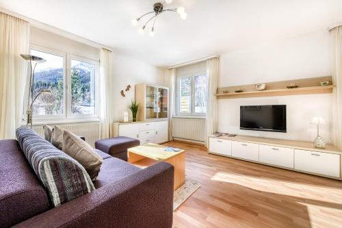 a living room with a couch and a tv at Haus Capricorn - Garten Appartement in Gargellen