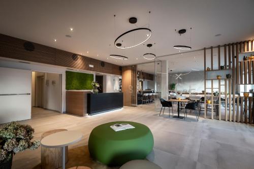 eine Lobby mit einer grünen Ottomane sowie einem Tisch und Stühlen in der Unterkunft Be Place Adult Friendly Hotel in Trient